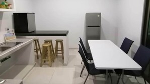 A modern kitchen with a dining area, including a white table, black chairs, and wooden stools.