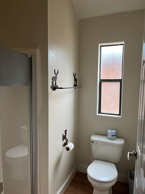 A bathroom with a toilet, a window, and a towel rack with deer-shaped hooks.
