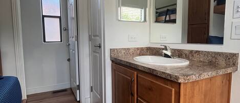 A bathroom with a vanity, sink, mirror, and ceiling fan.