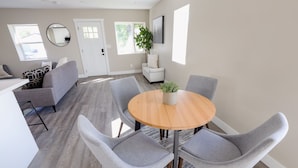 Un comedor moderno con una mesa redonda de madera, sillas tapizadas en gris y una planta en maceta.