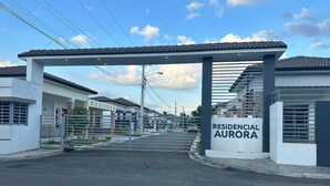 Ein geschlossener Wohnkomplex namens „RESIDENCIAL AURORA“ mit überdachter Zufahrt und modernen Gebäuden.