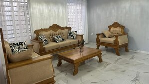 Ein Wohnzimmer mit einer Couch, zwei Sesseln, einem Couchtisch und einer Deckenleuchte.
