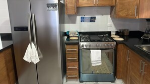Eine Küche mit Holzschränken, einem Edelstahlkühlschrank, einem Gasherd und einem Backofen.