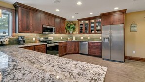 A modern kitchen with granite countertops, stainless steel appliances, and wooden cabinetry. - Great outdoor entertainment with slip on Cross Lake (Crosslake)