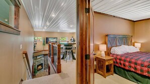 A cozy room with a fireplace, a dining area with a table and chairs, and a bed with a checkered bedspread. - Great outdoor entertainment with slip on Cross Lake (Crosslake)