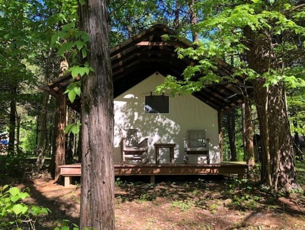 A rustic wooden cabin with a porch, surrounded by trees.