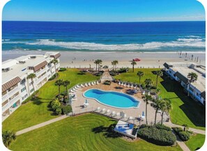 Vista aerea di un resort con piscina, accesso alla spiaggia e vista sull'oceano.