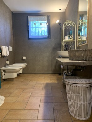 Ein Badezimmer mit großem Fenster, zwei Toiletten, einem Waschbecken und einem Spiegel.
