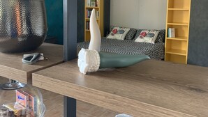 Un saló modern amb una taula de centre de fusta, un vas decoratiu blanc, un plat de pastissos de vidre i un sofà acollidor amb coixins estampats.