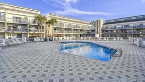 A hotel with a swimming pool, lounge chairs, and a tiled deck. - Endless Summer By Book That Condo (Panama City Beach)