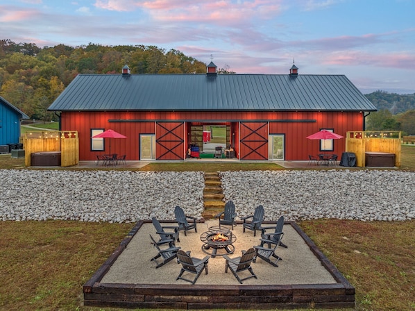 A rustic barn-style building with a gravel patio, outdoor seating, and a fire pit.