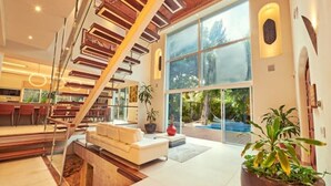 A modern interior with a staircase, a white sofa, and large windows. - Casa Los Charcos
 (Playa del Carmen)