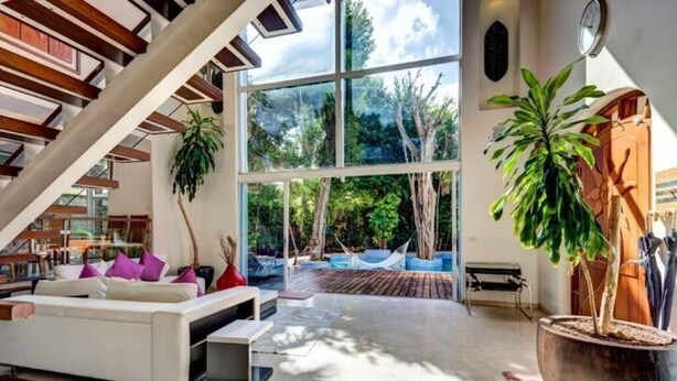 A spacious living area with a large glass wall, a staircase, and a potted plant. - Casa Los Charcos
 (Playa del Carmen)