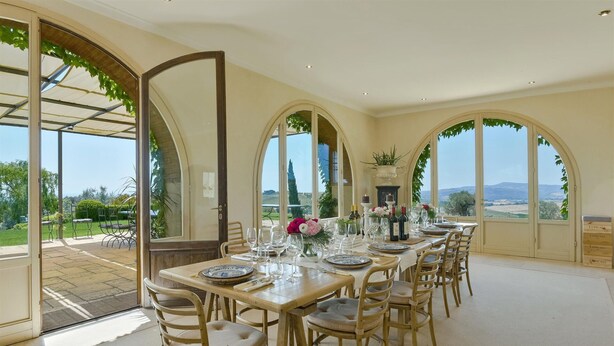 A dining area with a table set for six, large arched windows, and a view of the countryside. - Stunning private villa with private pool, WIFI, A/C, TV, pets allowed and panoramic view (Terriccio)