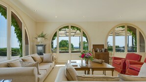 A spacious living room with a large table, two sofas, and a red armchair. There are arched windows with greenery and a view of the outdoors. - Stunning private villa with private pool, WIFI, A/C, TV, pets allowed and panoramic view (Terriccio)