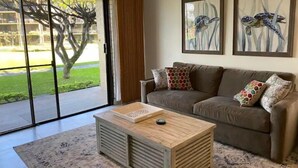 Ein Wohnzimmer mit einer Couch, einem Couchtisch und zwei gerahmten Kunstwerken.