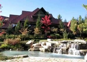 Un grand bâtiment avec un toit rouge, entouré d’arbres et d’une petite cascade.