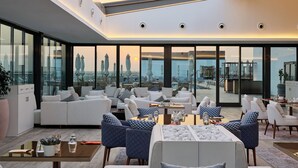 Een moderne woonkamer met uitzicht op de stad, grote ramen en eigentijds meubilair.