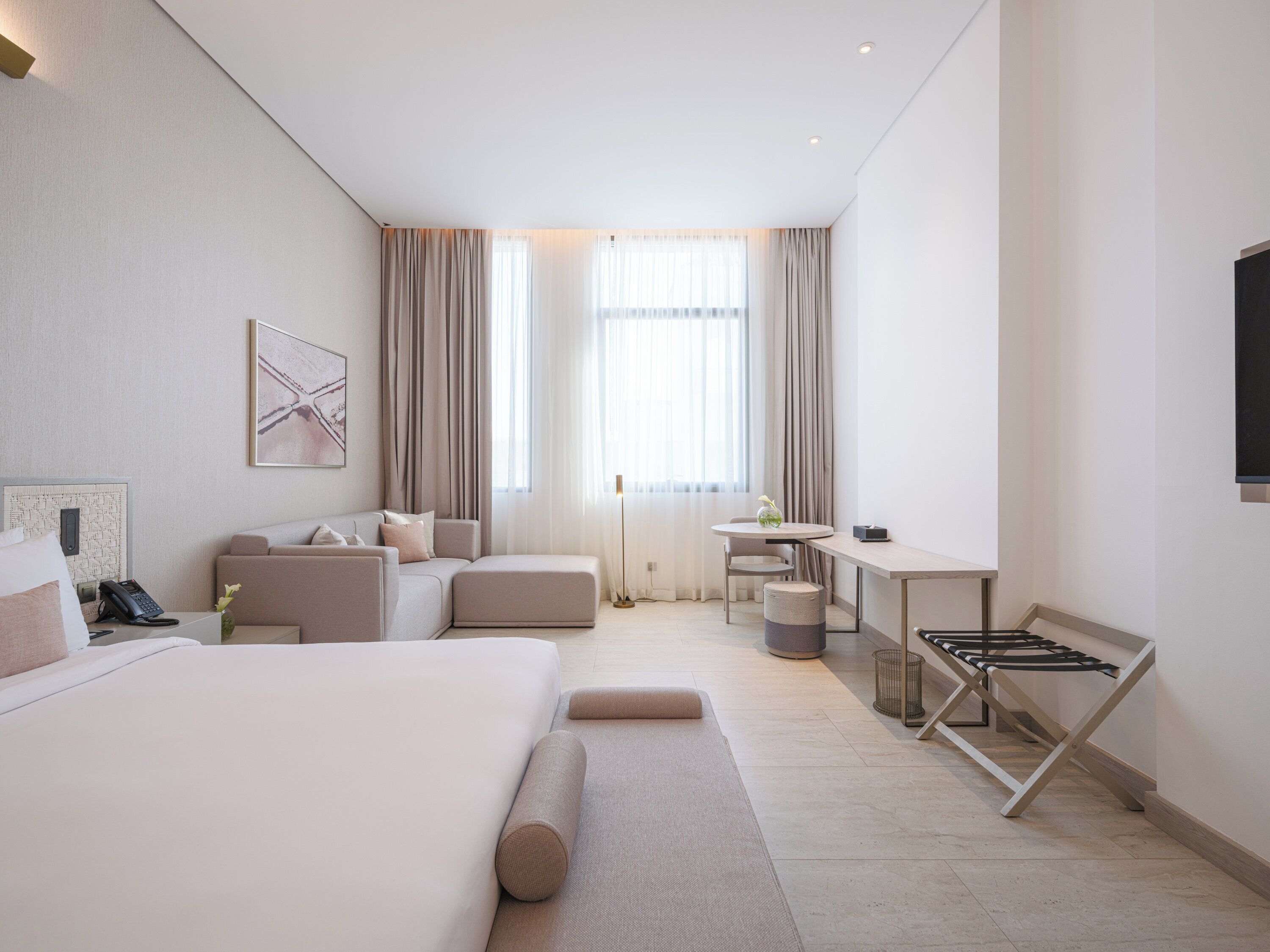 Una habitación de hotel moderna con una cama grande, un sofá, un escritorio y un televisor.