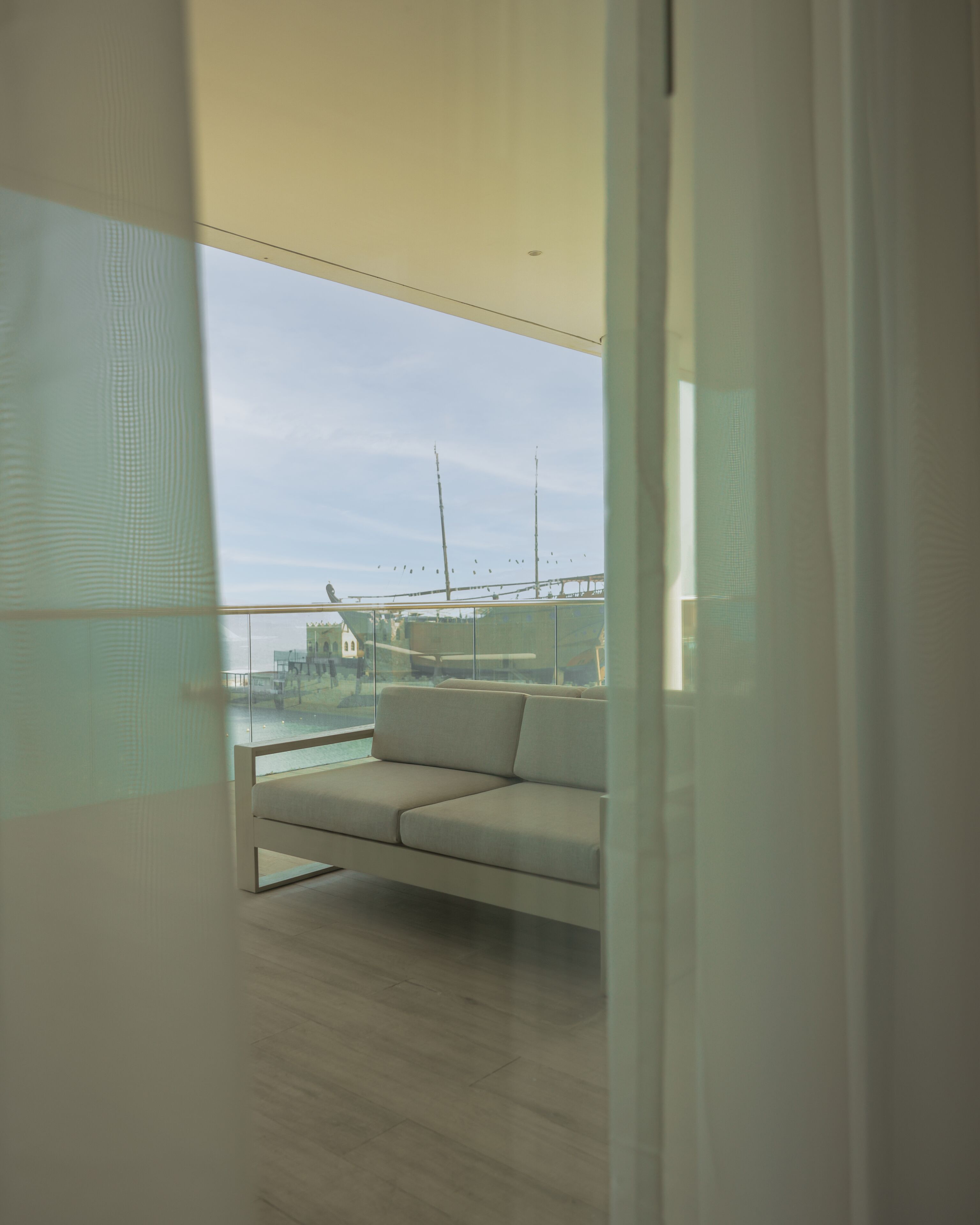 A balcony with a sofa, a view of a bridge, and a railing.