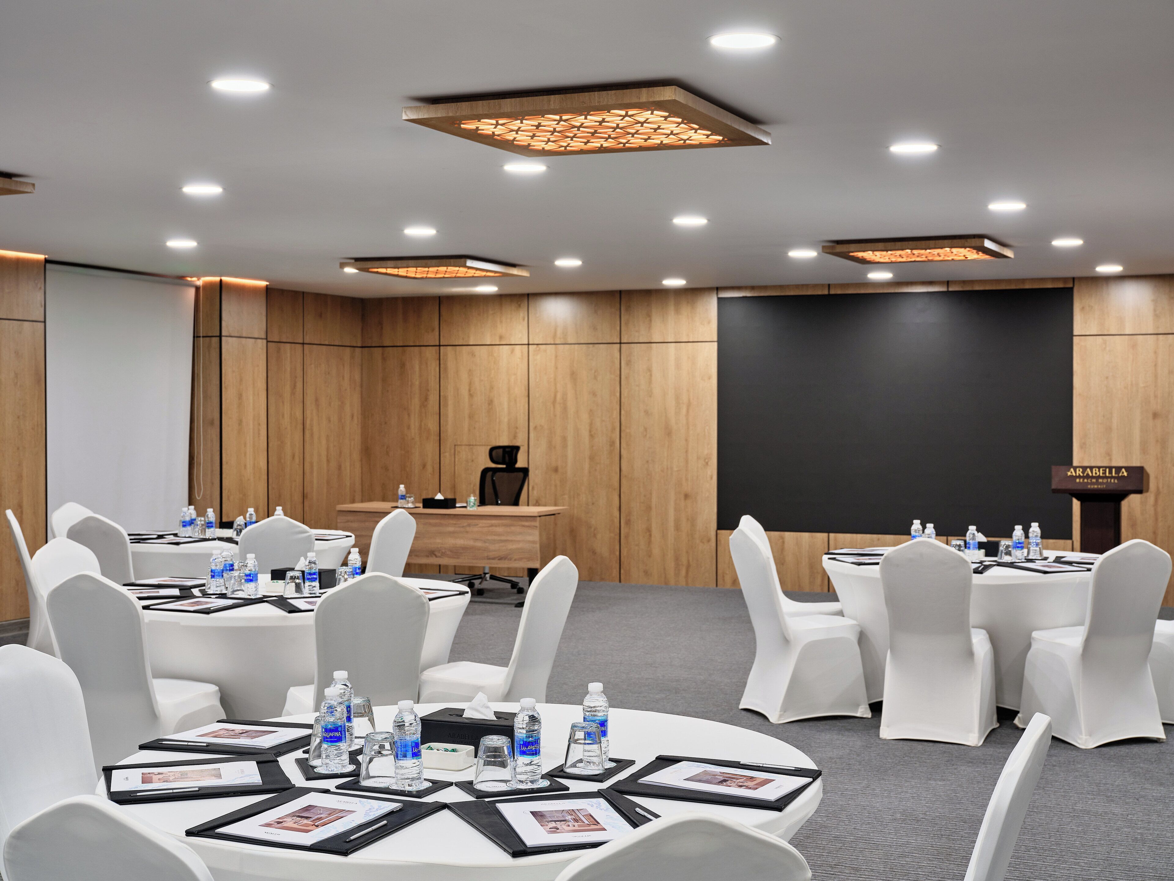 A conference room with round tables, white chairs, and water bottles.