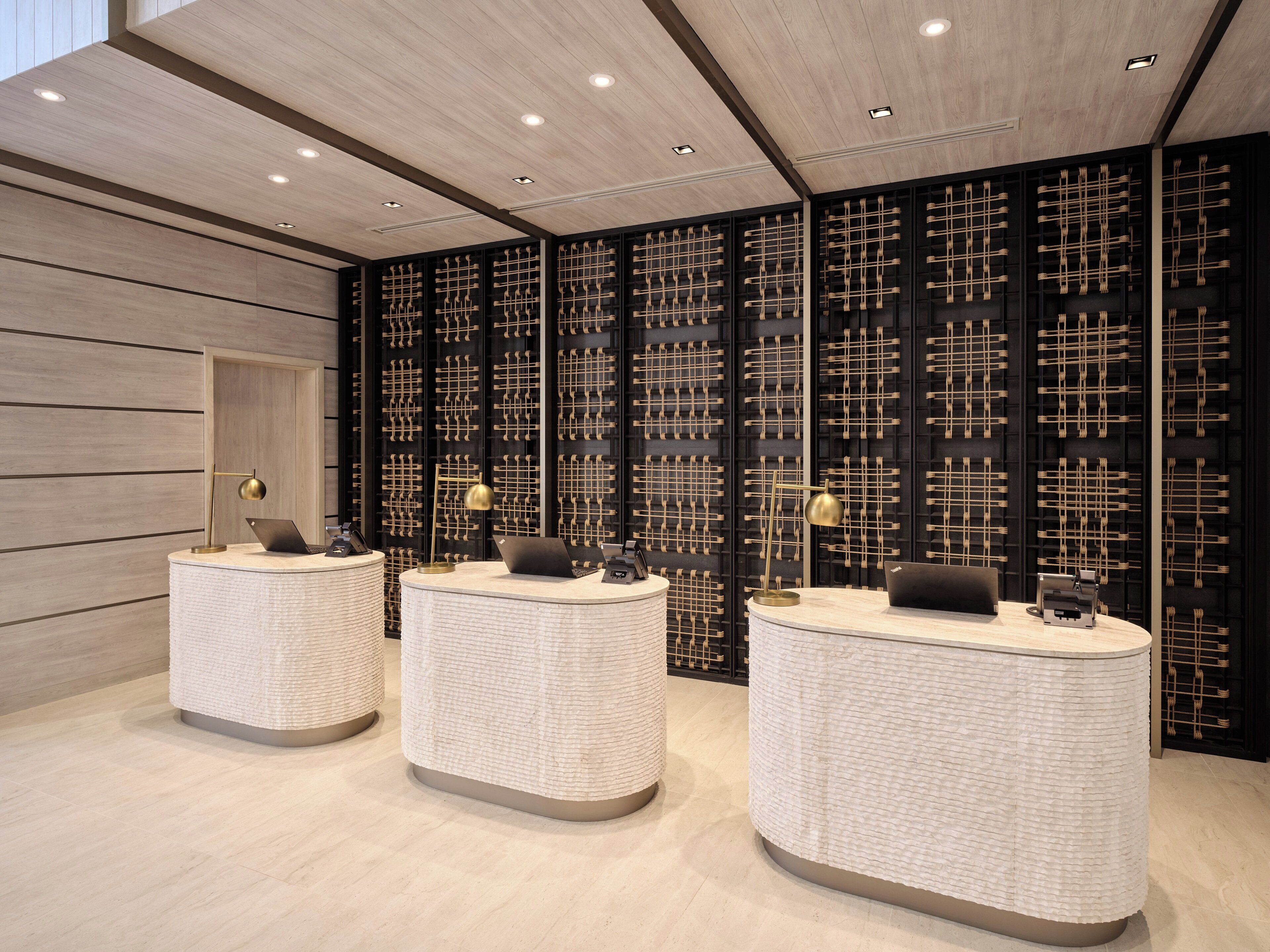 A reception area with three round, textured counters and a black wall with a woven pattern.