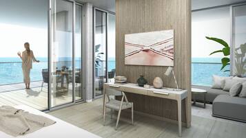 A modern living room with a desk, a sofa, and a large window overlooking the sea.