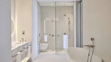 Un baño moderno con ducha de vidrio, una bañera independiente y un tocador con encimera de mármol.