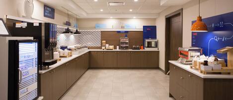 A modern kitchen area with a refrigerator, coffee machine, and a bakery section.
