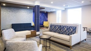 A modern lounge area with a sofa, armchairs, a coffee table, and a patterned throw pillow. - Holiday Inn Express and Suites Prince Albert South by IHG (Prince Albert)