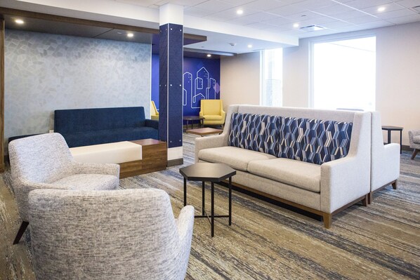 Un espace de détente moderne comprenant un canapé, des fauteuils, une table basse et un coussin décoratif à motifs.