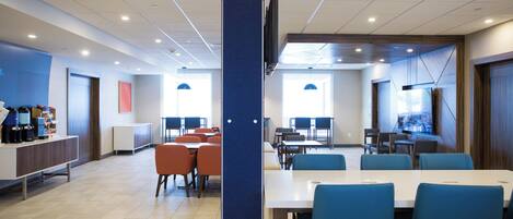 A modern conference room with tables and chairs, a coffee station, and a large screen.