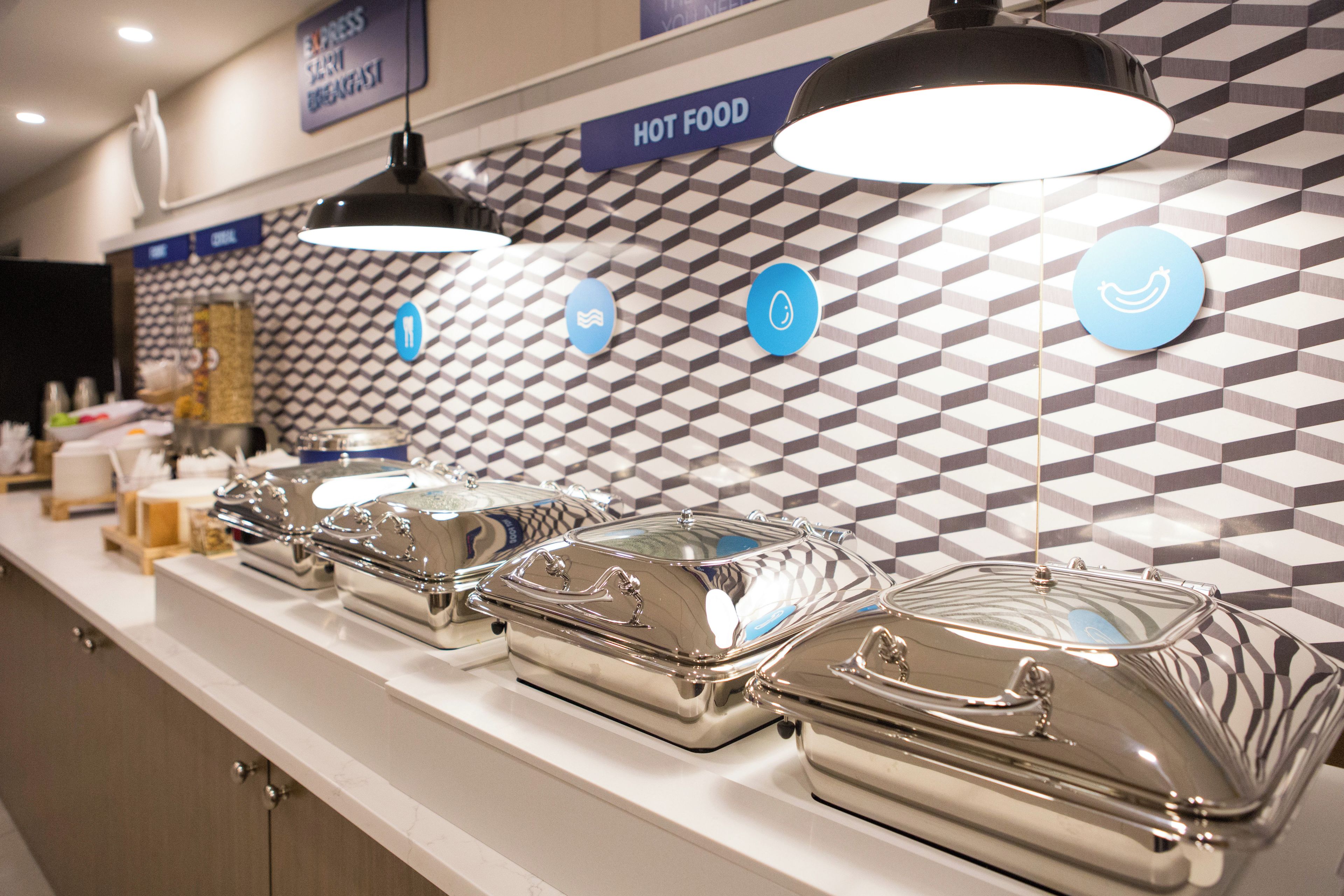 A buffet area with multiple serving stations, each with a covered dish and a blue sign.