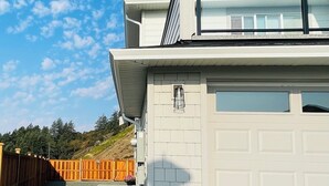 A two-story house with a garage door, a covered porch, and a wooden fence. - Full Comfy&Private Suite with a Yard for Your Getaway in Bear Mountain, Victoria (Victoria)