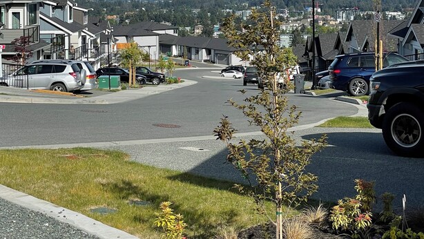 A residential street with houses, parked cars, and a clear view of a distant cityscape. - Full Comfy&Private Suite with a Yard for Your Getaway in Bear Mountain, Victoria (Victoria)