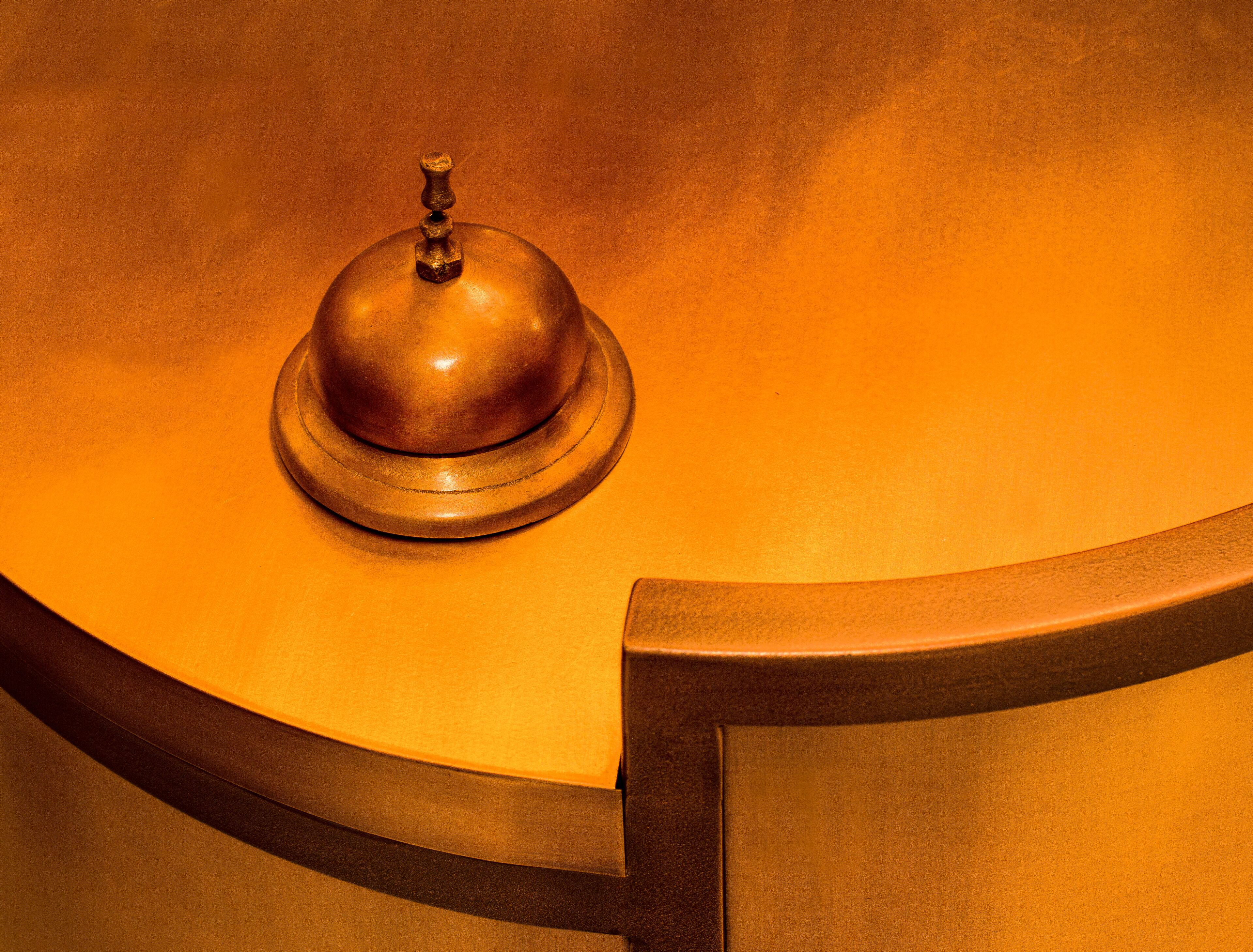 A close-up of a brass bell on a curved, metallic surface, likely part of a room's interior design.