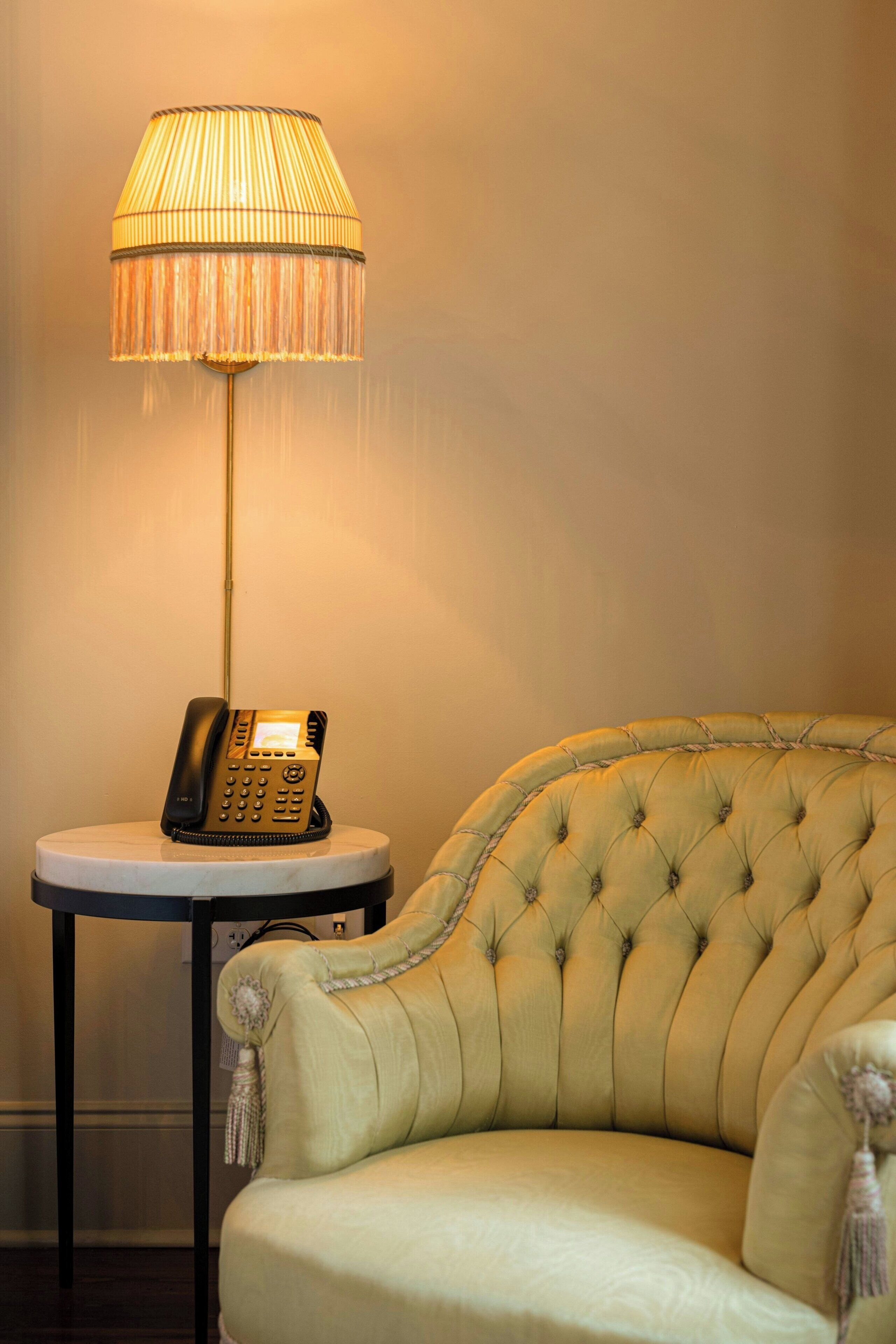 Un sillón con textura y un teléfono sobre una pequeña mesita auxiliar.