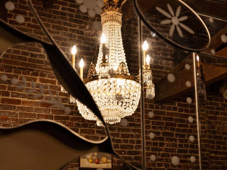 Un lustre orné de nombreuses bougies, un mur en briques et un tableau encadré.