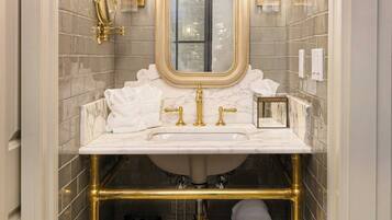Une salle de bain dotée d’un lavabo en marbre, de robinetterie dorée, d’un grand miroir et d’un porte-serviettes avec des serviettes.