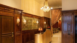 A reception area with a wooden reception desk, a chandelier, and a mural on the wall.