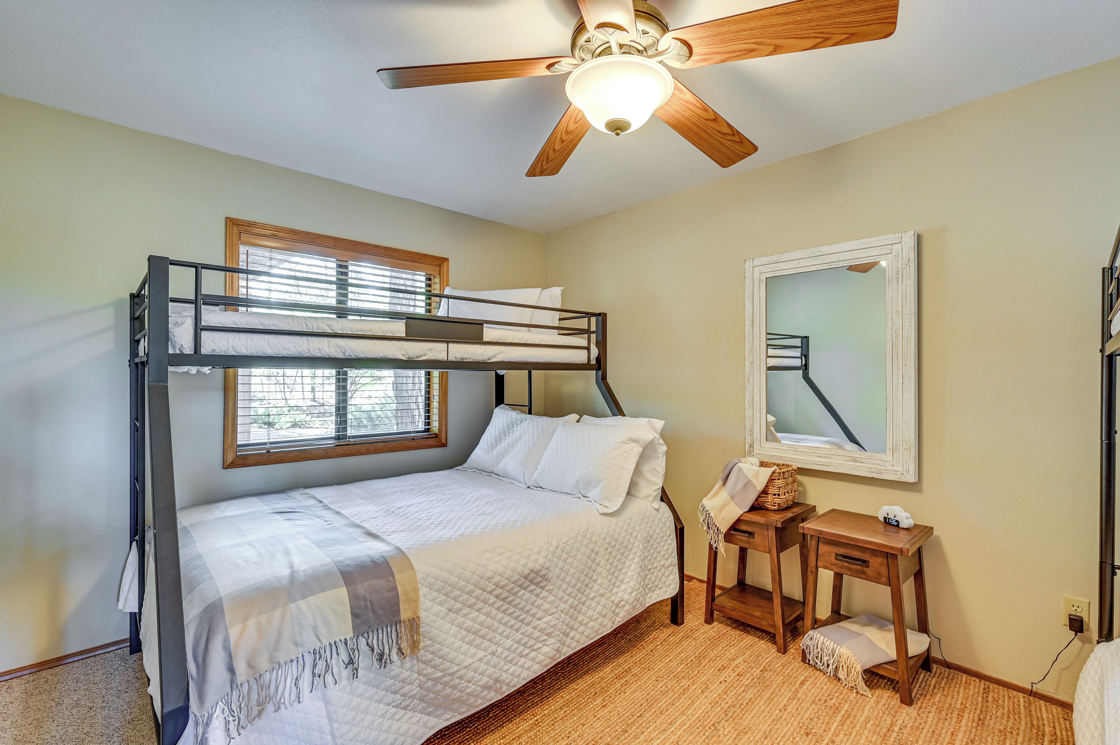 A bunk bed room with a ceiling fan, a desk, and a mirror.