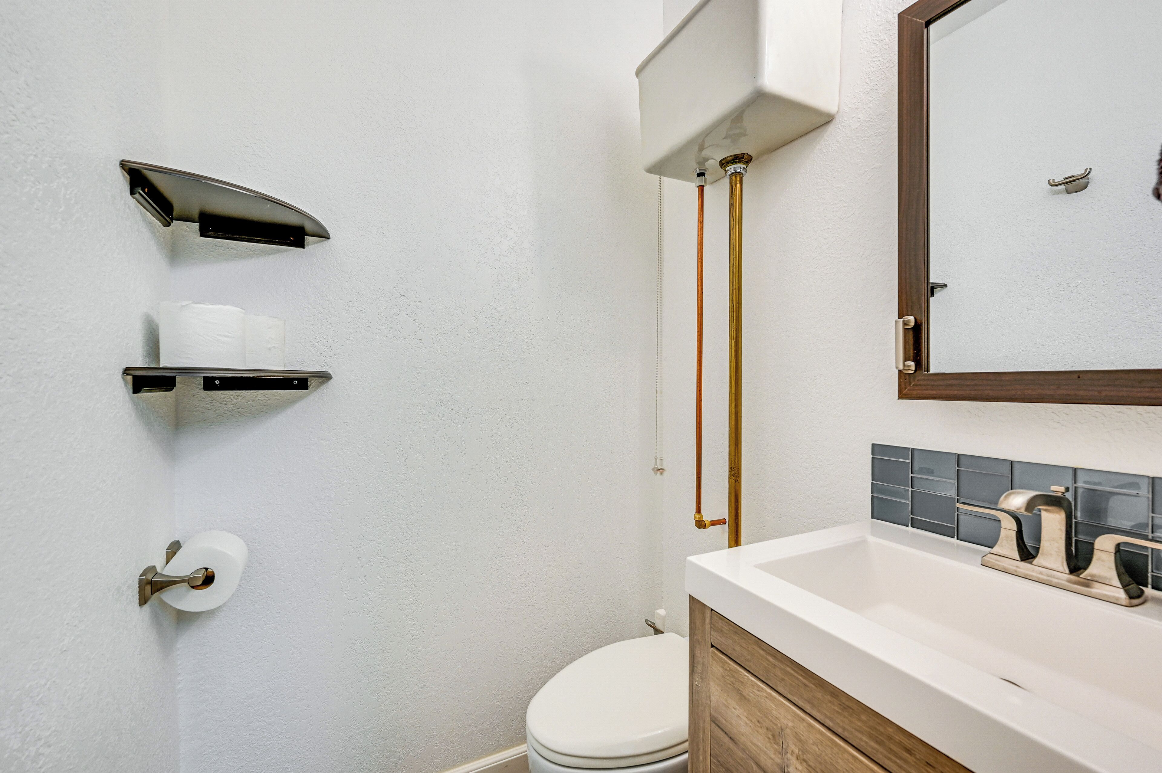 A bathroom with a toilet, a sink with a mirror, and a towel rack.