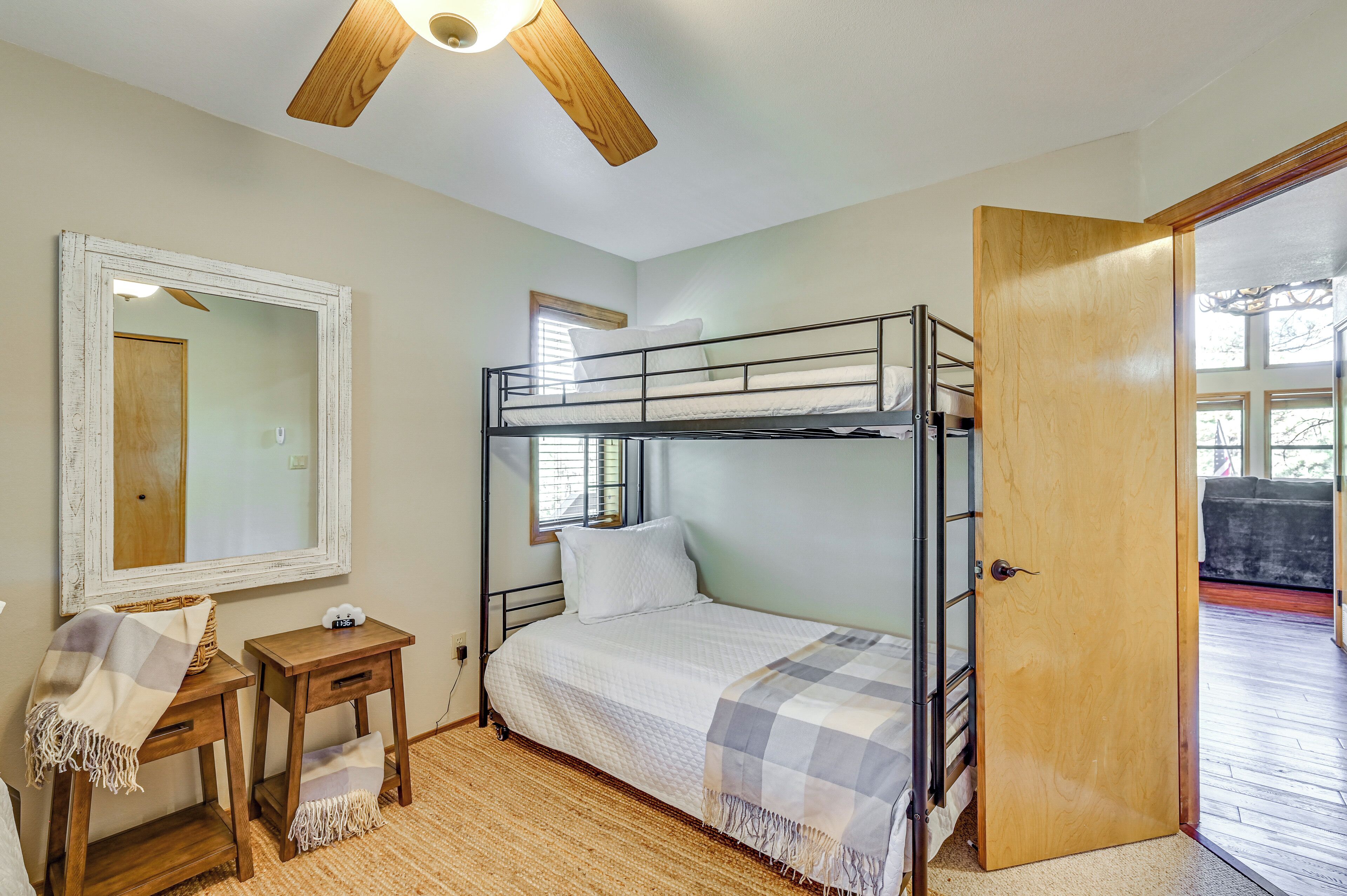 A bunk bed room with a wooden door, a small table, a mirror, and a window.