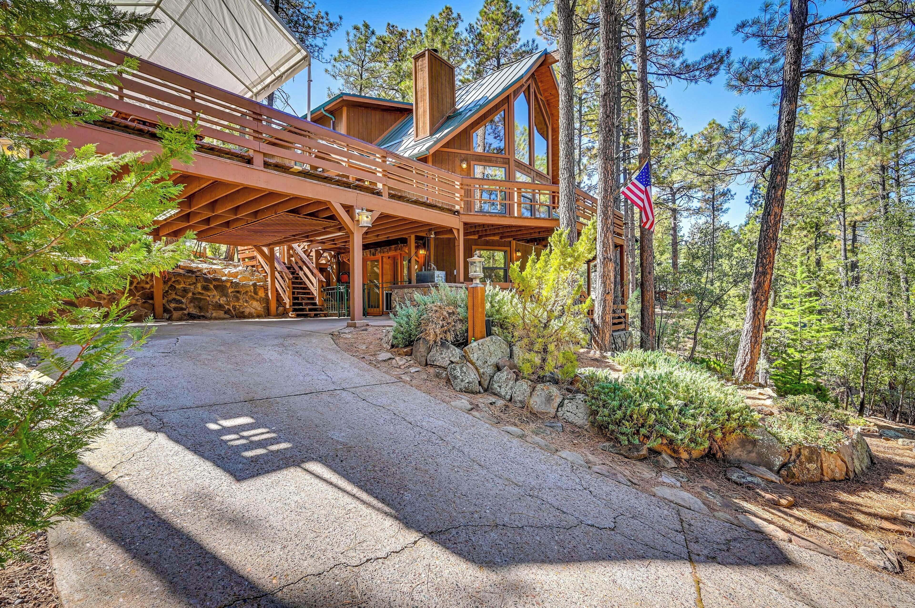 A wooden cabin with a stone foundation, a covered porch, and a flag.