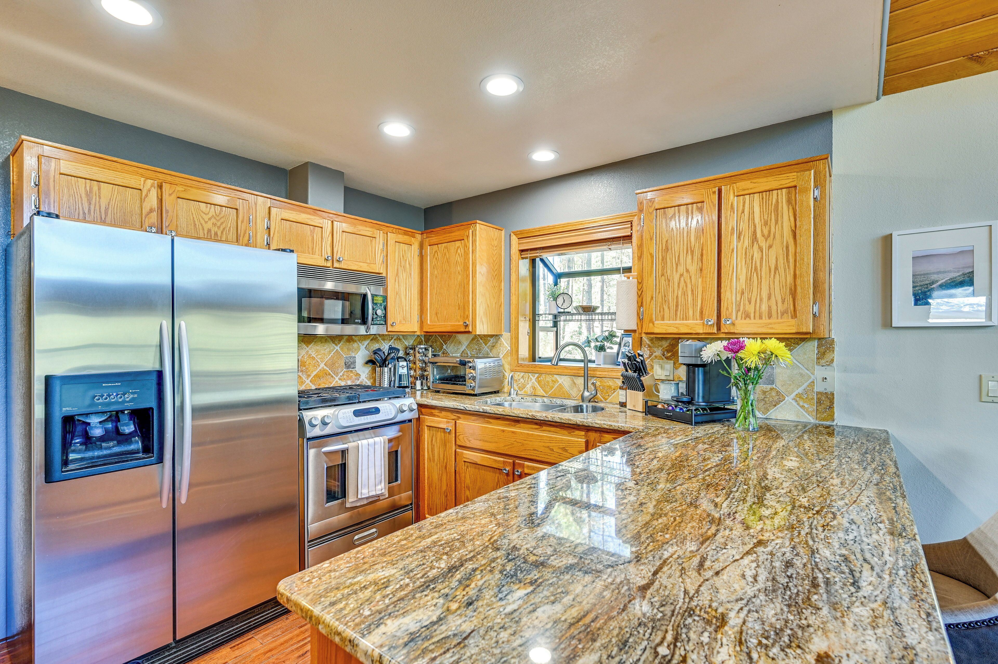 A kitchen with wooden cabinets, stainless steel appliances, granite countertops, and a water dispenser.