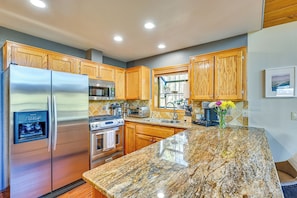 A kitchen with wooden cabinets, stainless steel appliances, granite countertops, and a water dispenser.