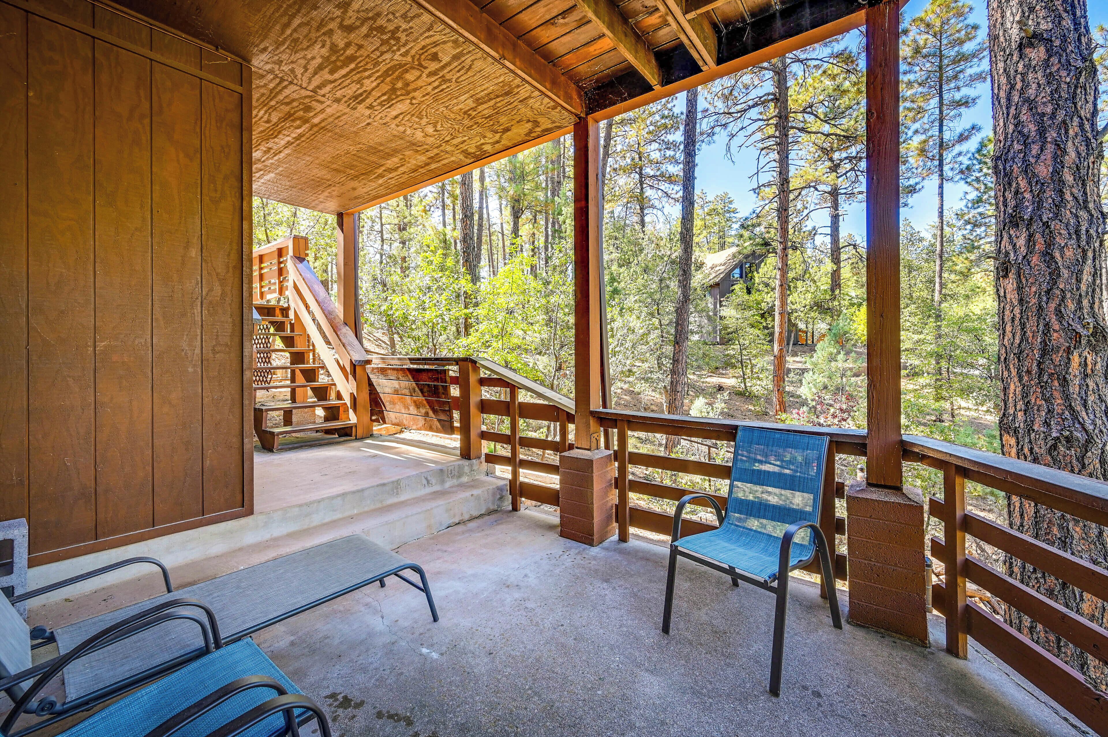 A wooden cabin with a balcony overlooking a forest.