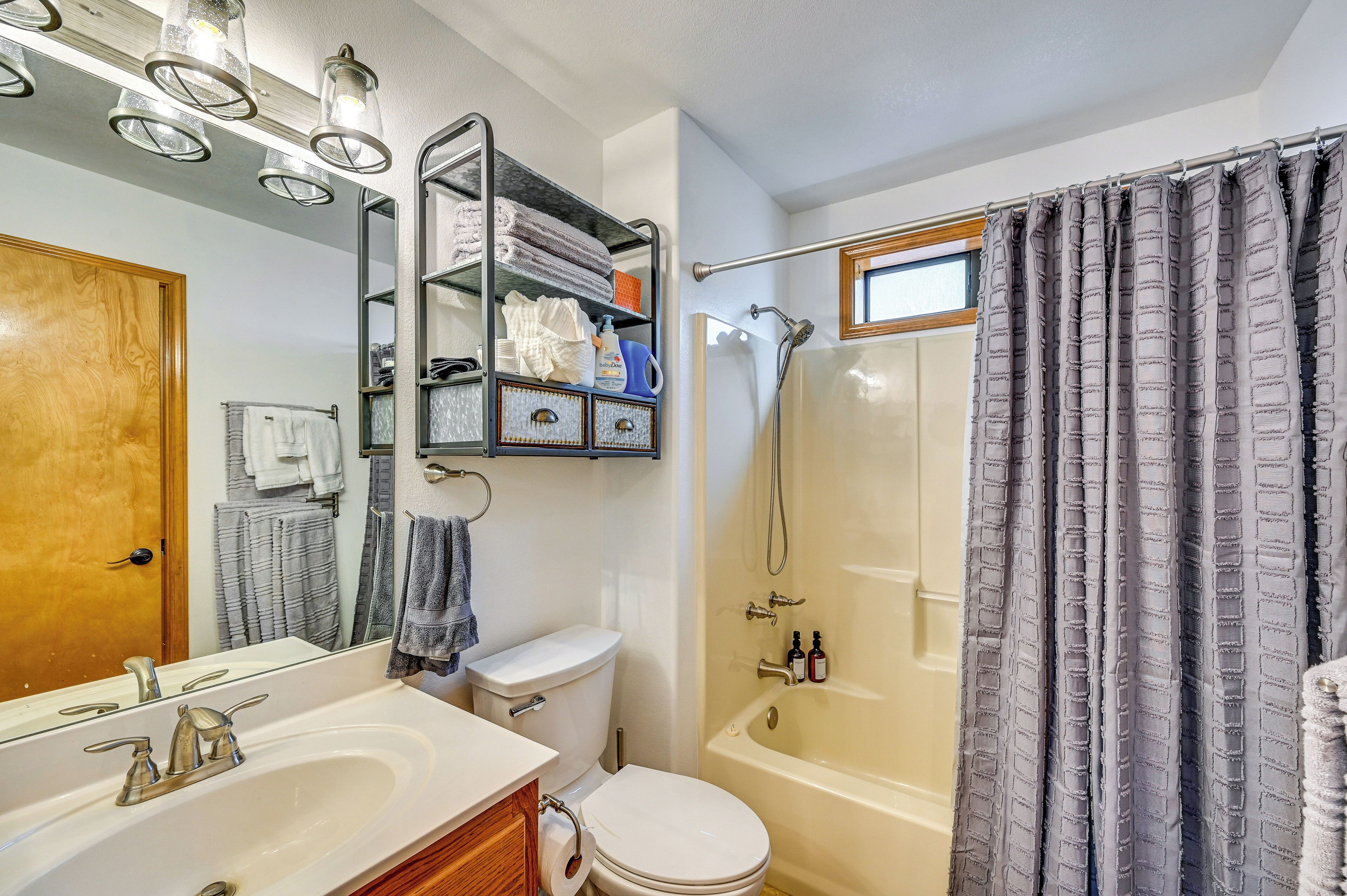A bathroom with a white sink, a toilet, a shower with a glass door, and a towel rack with folded towels.