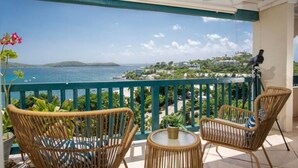 A balcony with wicker chairs and a small table, overlooking a coastal view with a camera on a tripod. - Gigi's Luxury Beach Hideaway- 3 BDRM- Cowpet Bay West- East End- Pool & Beach
 (St Thomas)