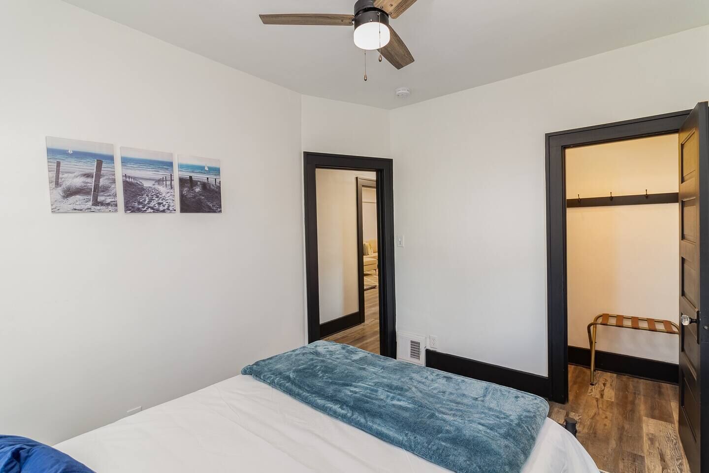 Ein Schlafzimmer mit einem Bett, einem Deckenventilator und einer Tür zu einem weiteren Raum.